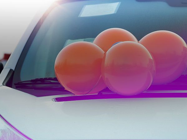 Des ballons de baudruche orange sont attachés en grappe sur le devant d’une voiture